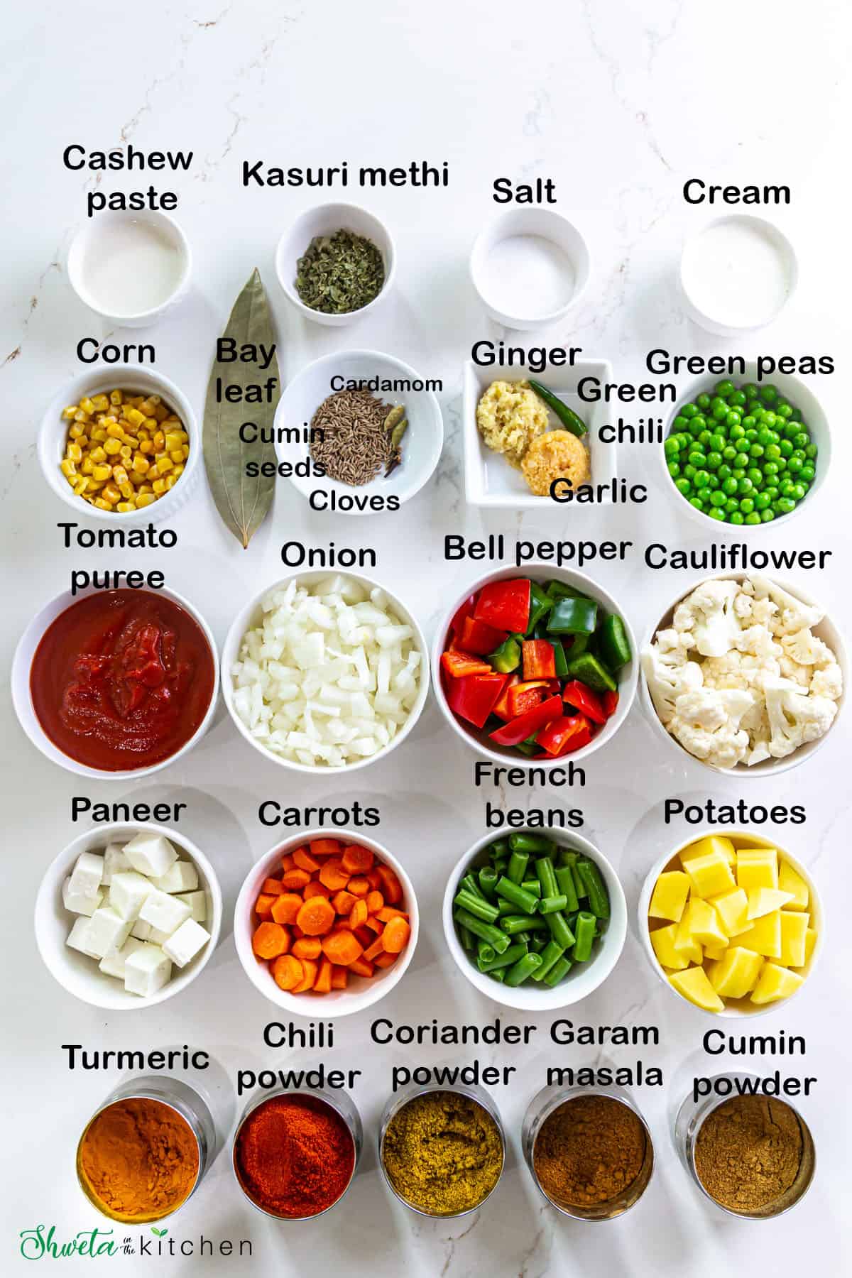 Ingredients for mixed vegetable curry placed in bowls on a white surface