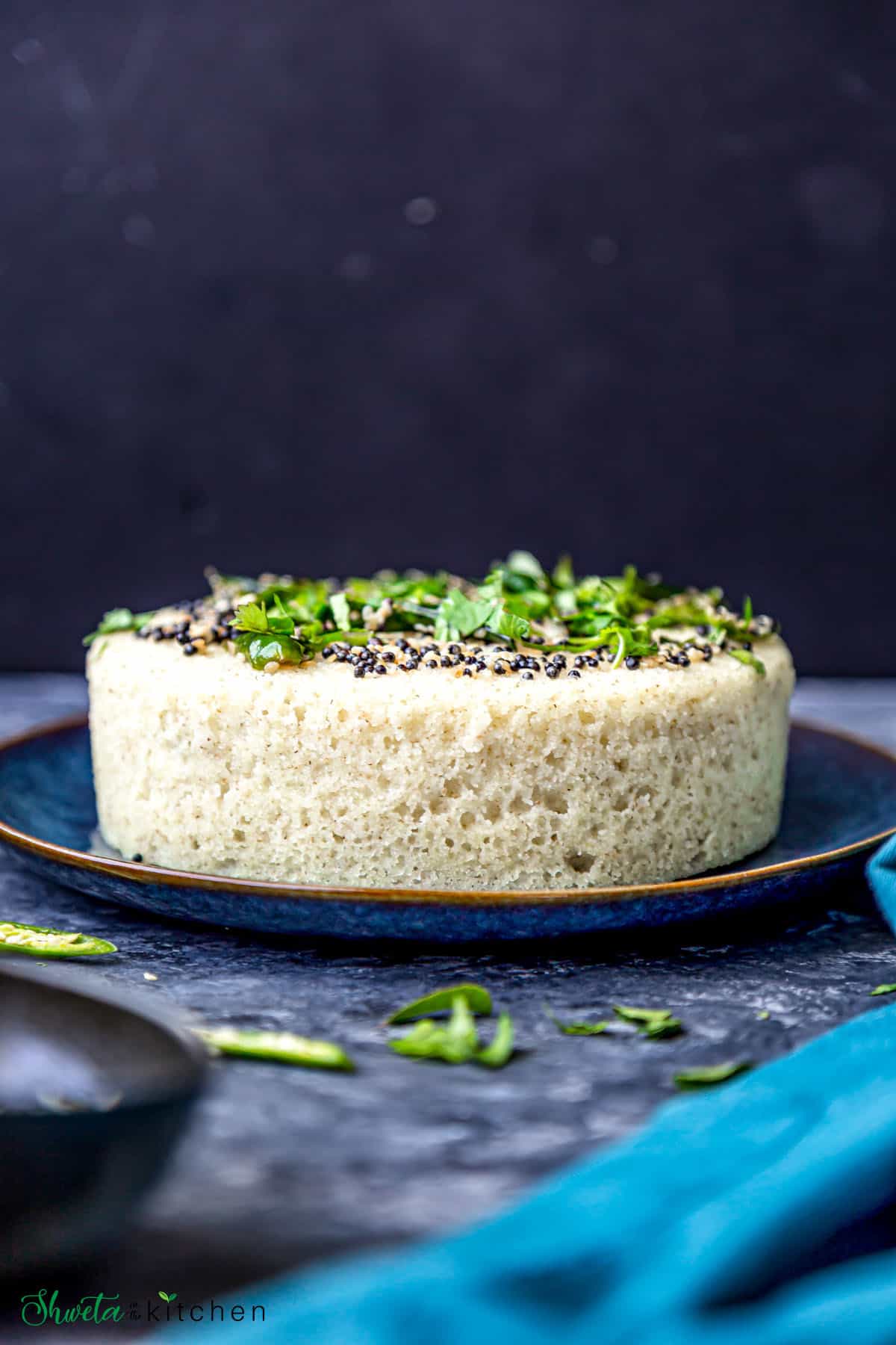 Side view of Rava Dhokla with tempering placed on blue plate