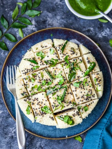 top view of Rava dhokla with tempering cut into pieces and placed on blue plate