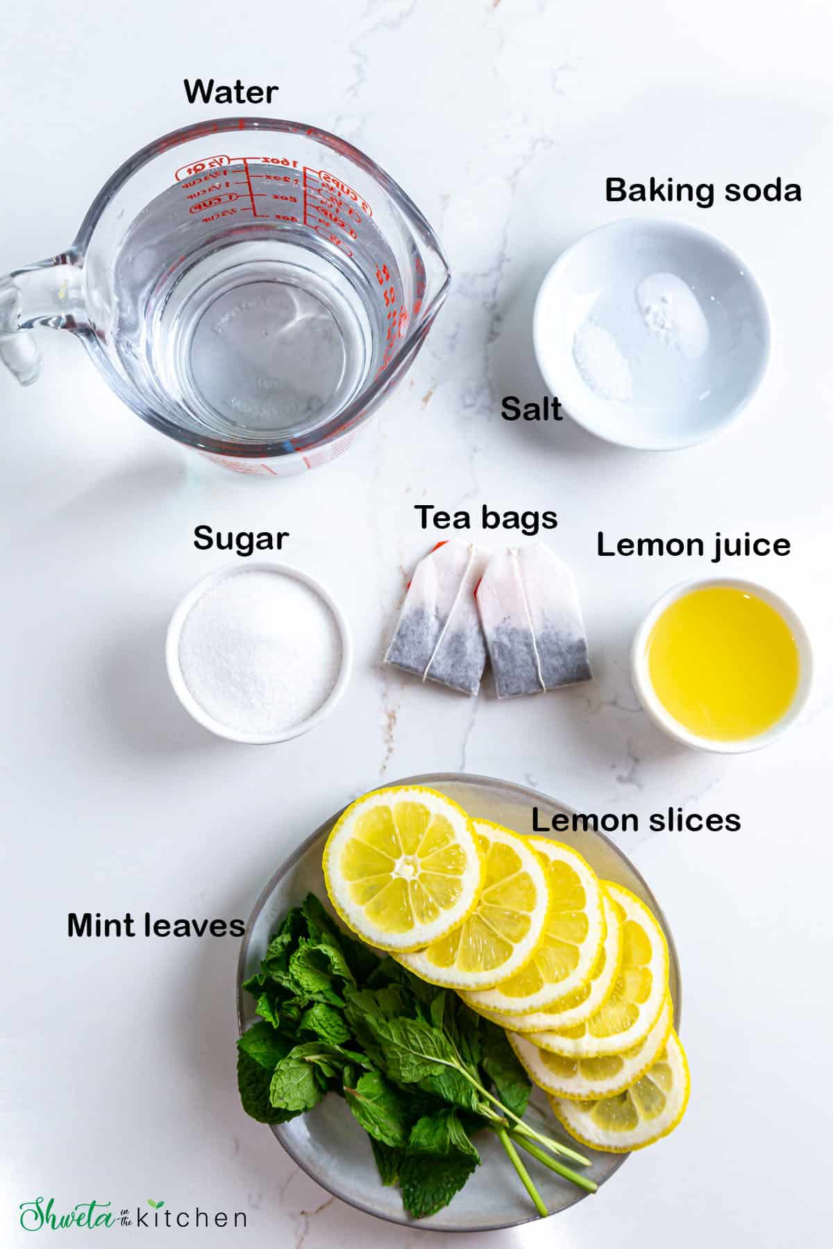 Ingredients for lemon iced tea placed on white surface