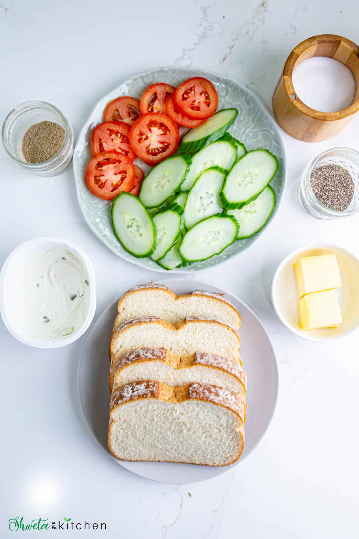 Ingredients for tomato cucumber sandwich placed on white surface
