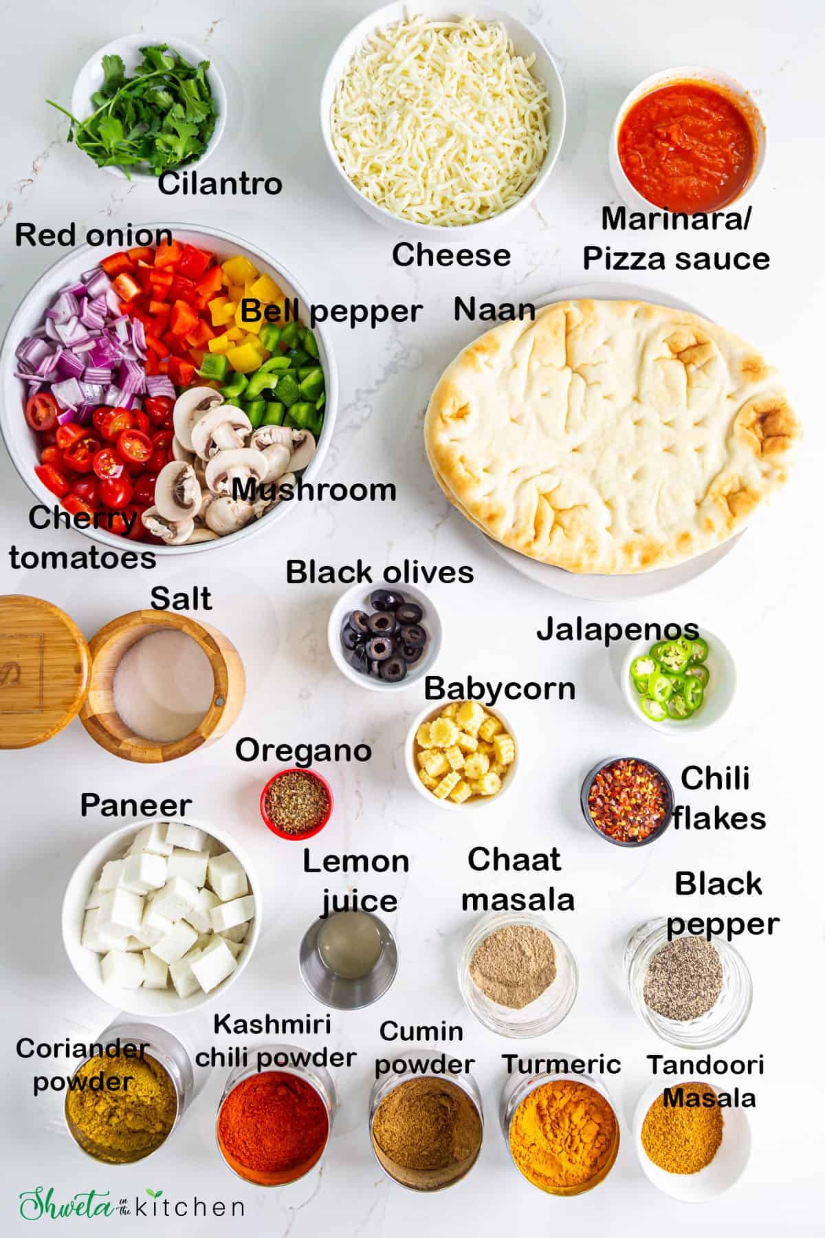 Ingredients for paneer naan pizza placed in bowls on white surface