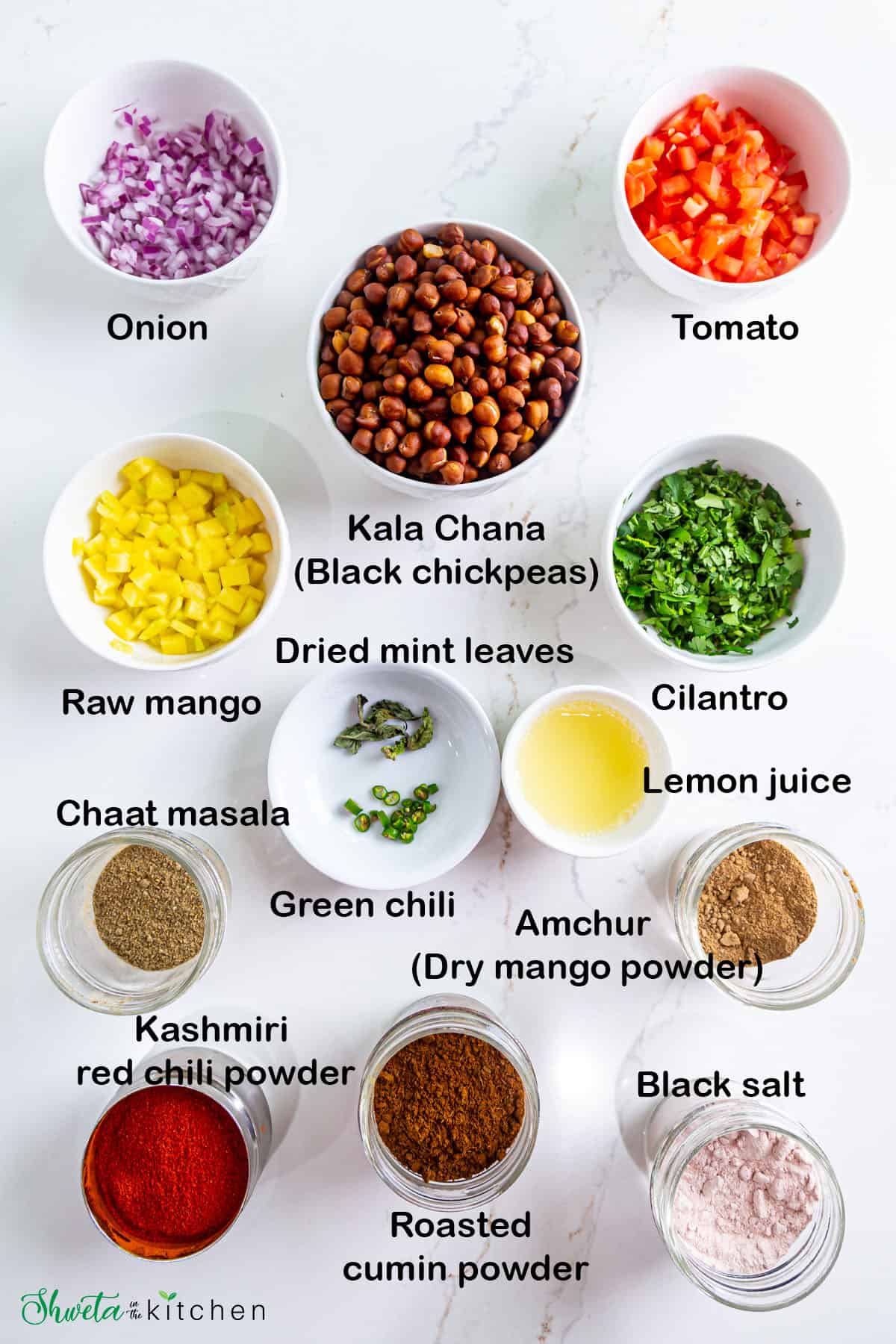 Ingredients for kala chana chaat (black chickpea salad) placed in bowls on white surface