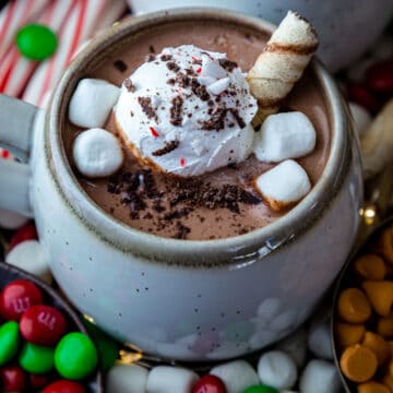 Hot chocolate in a mug topped with cream, marshmallows and rolled wafer