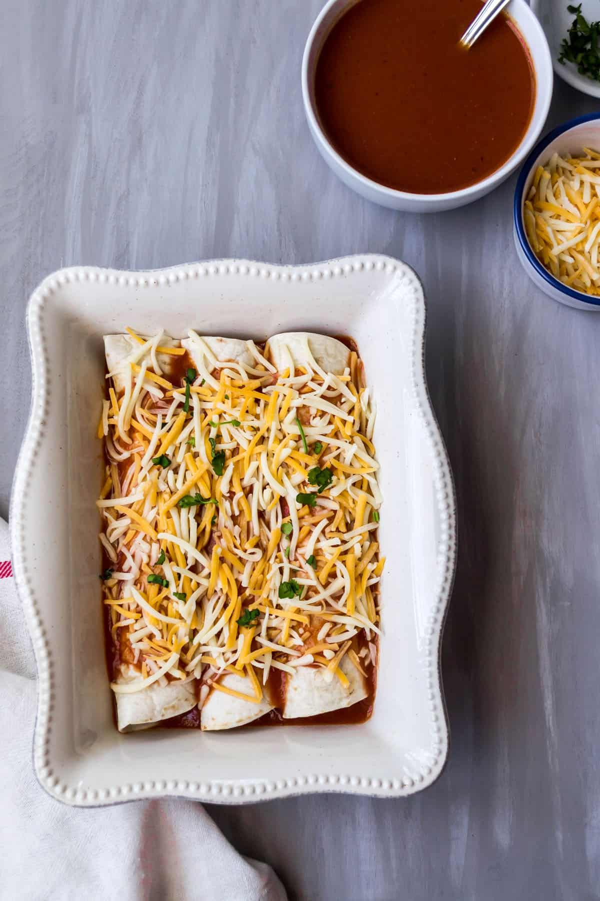 The enchiladas topped with shredded cheese before being baked