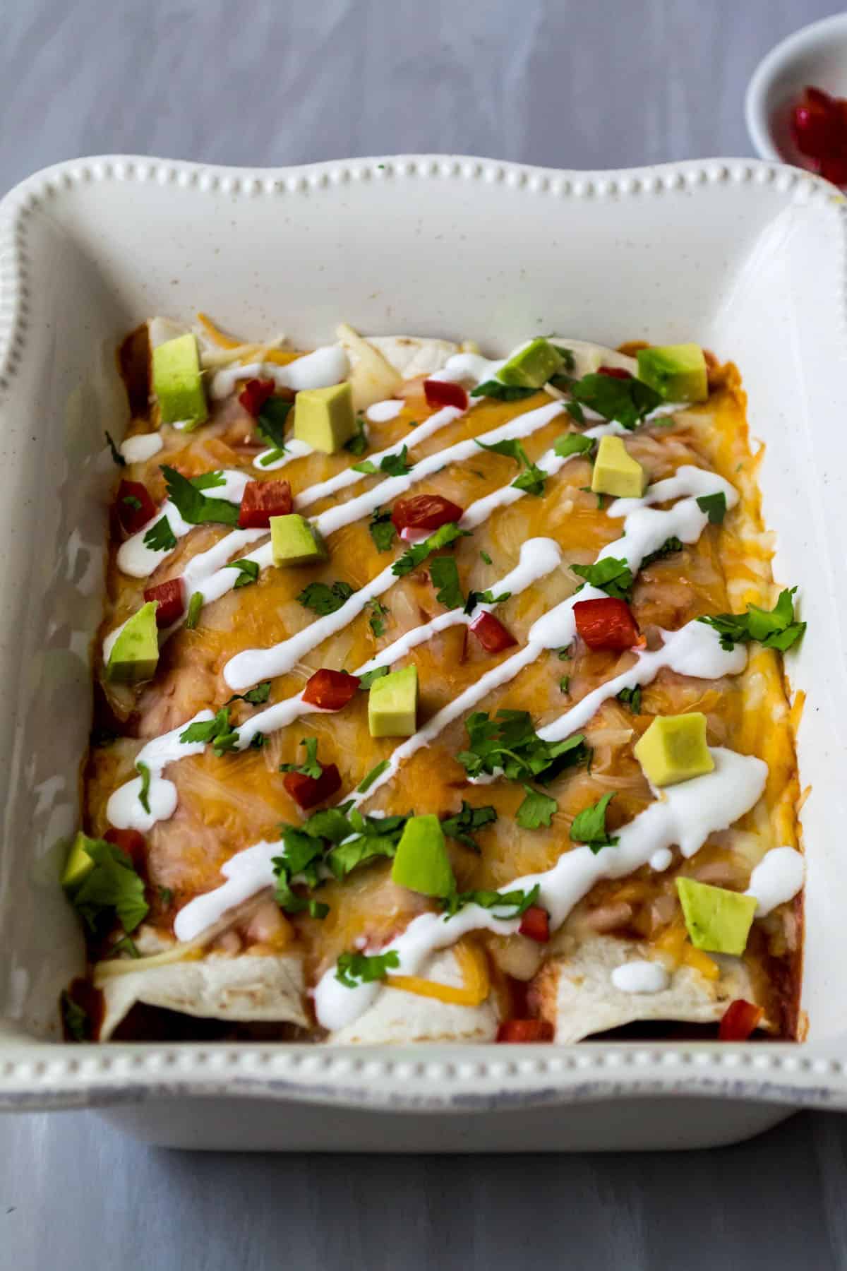 Side view of baked black bean enchiladas in a white dish