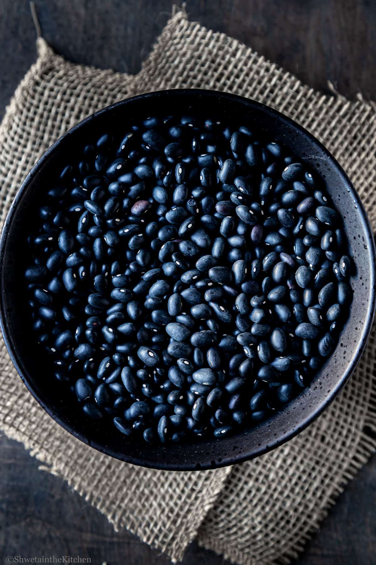 Top view of dried black beans in a black bowl