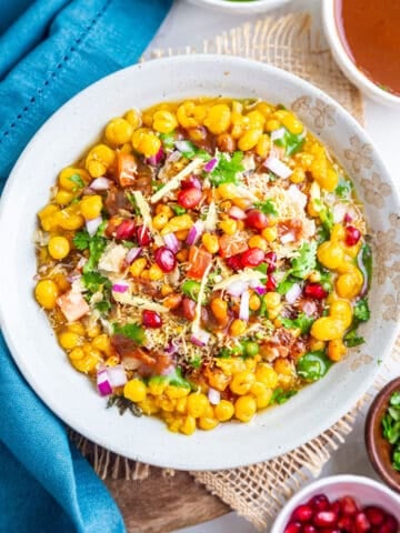 Top view of ragda chaat in white bowl garnished with chutney and toppings
